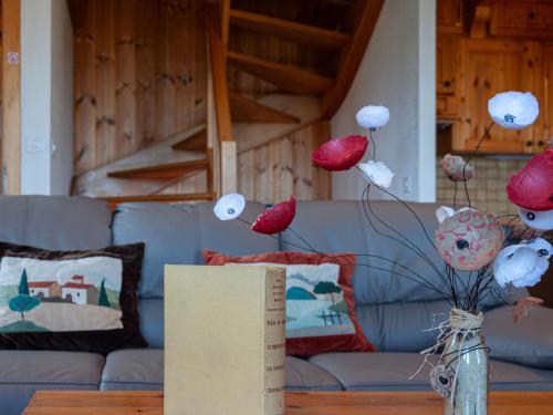 a vase of flowers on a table with a couch at Chalet Valet de Coeur by Interhome in Nendaz