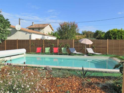 a swimming pool with chairs and a fence at Holiday Home Mon Poussin - SVV120 by Interhome in Saint-Vivien-de-Médoc