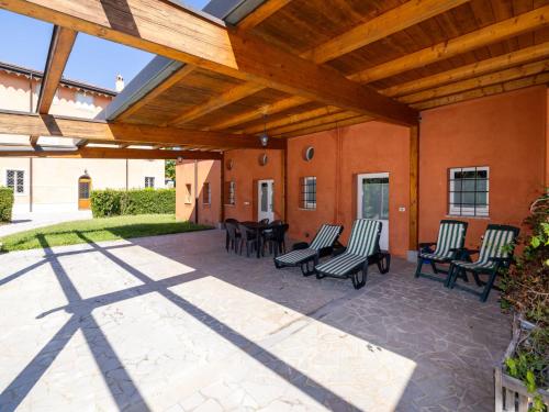 un patio con sillas, mesas y una pérgola de madera en Apartment Winery Villa Vitas Dépendance - App-2 by Interhome en Strassoldo