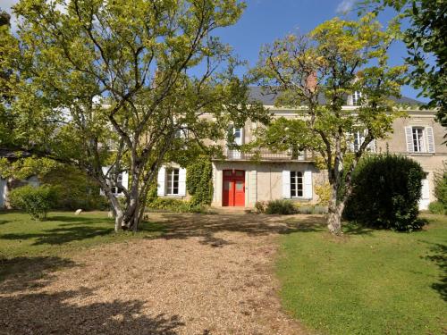 a white house with a red door and trees at Holiday Home Langevine by Interhome in Thorigné-dʼAnjou