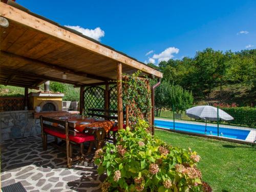 a wooden pergola with a table and chairs next to a pool at Holiday Home Michael e Patrick by Interhome in Magnano
