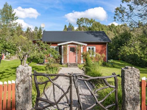 a red house with a wooden gate in front of it at Holiday Home Bredasjö by Interhome in Gnitteryd