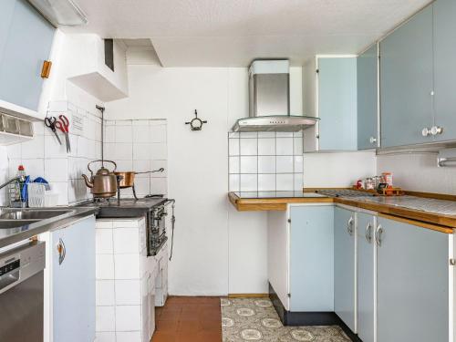 a small kitchen with blue cabinets and white tiles at Holiday Home Bredasjö by Interhome in Gnitteryd