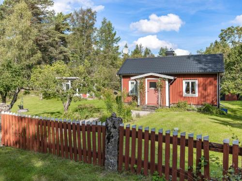 a red house with a fence and a yard at Holiday Home Bredasjö by Interhome in Gnitteryd