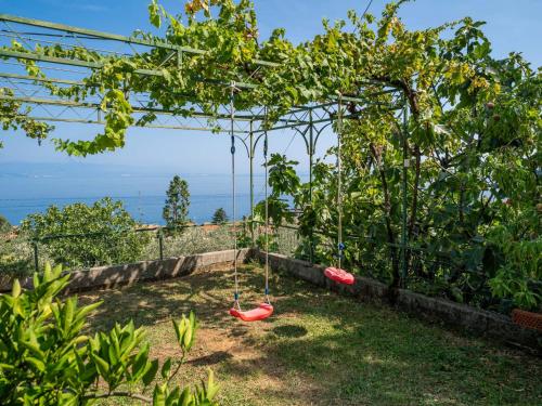 a swing set in a garden with trees at Apartment Emil by Interhome in Lovran