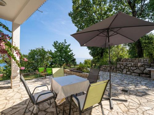 a table and chairs with an umbrella on a patio at Apartment Emil by Interhome in Lovran