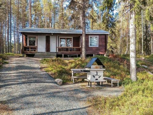 uma cabana de madeira na floresta com uma churrasqueira na frente em Holiday Home Ylikitkajärvi- kesäkumpu by Interhome em Orjasniemi