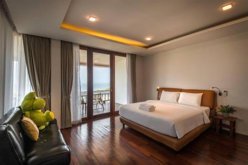Phi Phi Mountain Beach Resort SHA Certified في جزيرة في في: غرفة نوم بسرير وكرسي وشرفة