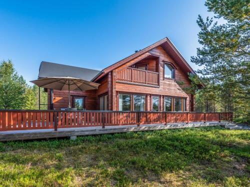 a log cabin with a deck and an umbrella at Holiday Home Lapinukonkäännös - incl- 1 ski pass by Interhome in Ruka