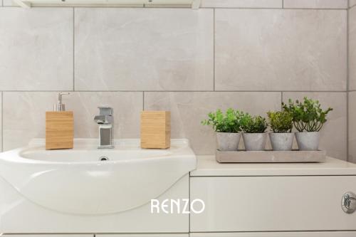 a bathroom with a sink and two potted plants at Bright and Warm 3-bed Home in Nottingham by Renzo, Free Driveway Parking, Close to Wollaton Park! in Nottingham