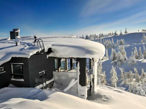 a house covered in snow with trees in the background at Holiday Home Rukavuorenhuippu 23 a by Interhome in Ruka