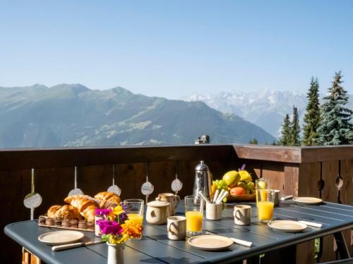 a table with bread and fruit on a balcony with mountains at Apartment Licorne 13 by Interhome in Verbier