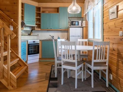 LahdenperäにあるHoliday Home Noukatti by Interhomeのキッチン(緑のキャビネット、テーブル、椅子付)
