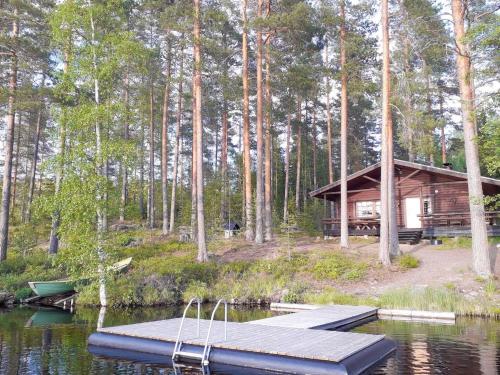 a cabin on a lake with a dock and a boat at Holiday Home Aaretti by Interhome in Arrakoski