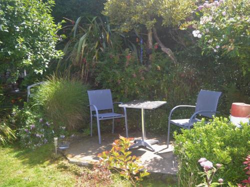 2 chaises et une table dans un jardin dans l'établissement Holiday Home Ti Maen by Interhome, à Kernalléguen