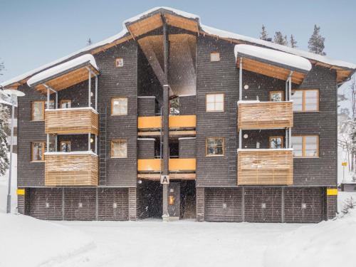 a building with wooden balconies in the snow at Holiday Home Karhunvartijan linna a3 by Interhome in Ruka