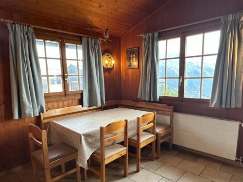 a dining room with a table and chairs and windows at Chalet Chalets Tsamandon by Interhome in Nendaz