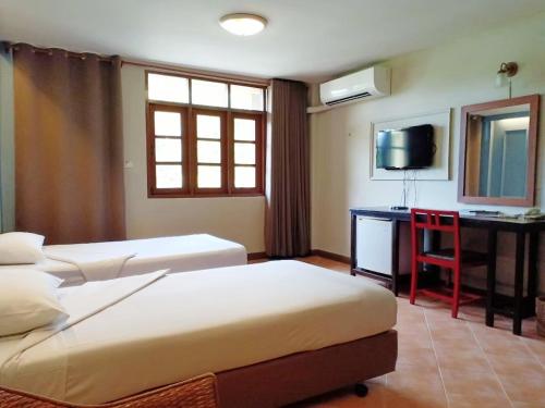 a hotel room with two beds and a desk and a television at Sun Hotel in Phetchaburi