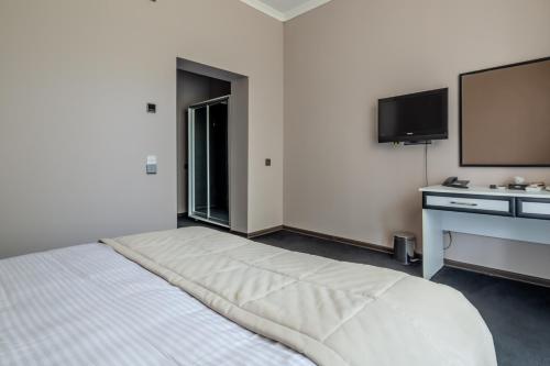 a bedroom with a bed and a flat screen tv at Mona Hotel and Cottages in Lankaran