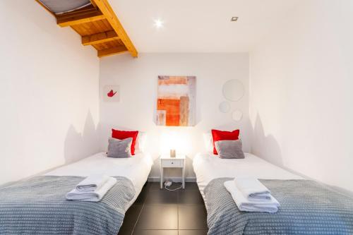 two beds in a room with white walls and red pillows at Casa dos Mouros - 2 Quartos e Cozinha - Serra da Estrela - Loriga in Loriga