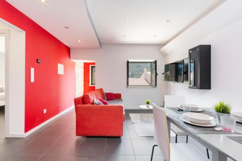 a living room with a red accent wall and a red chair at Casa dos Mouros - 2 Quartos e Cozinha - Serra da Estrela - Loriga in Loriga