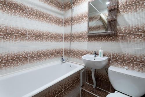 een badkamer met een bad, een toilet en een wastafel bij Majestic in Petropavlovsk