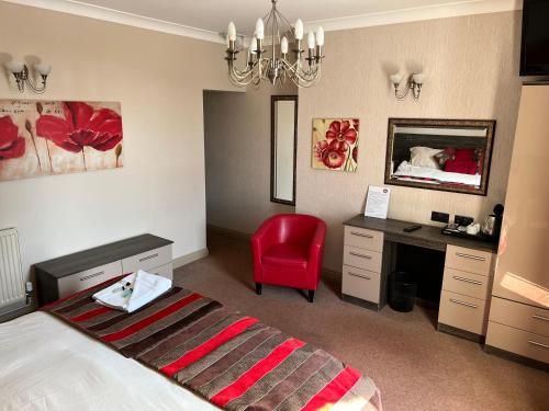 a bedroom with a bed and a desk and a red chair at Southport Metro Hotel in Southport