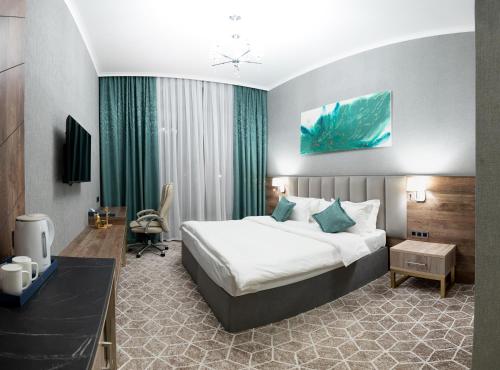 um quarto de hotel com uma cama grande e uma secretária em Tauke Khan Plaza em Shymkent