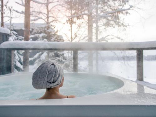 Eine Frau in einem Whirlpool im Schnee in der Unterkunft Holiday Home Villa uggo 4 skipasses included 2024-25 by Interhome in Hyrynsalmi