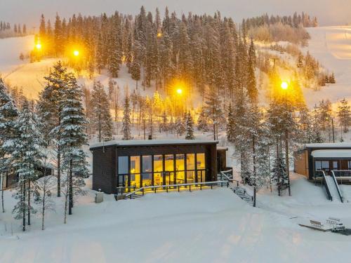 a house in the snow with lights on at Holiday Home Villa uggo by Interhome in Hyrynsalmi