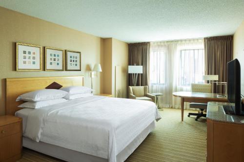 Habitación de hotel con cama blanca grande y escritorio. en Sheraton Atlantic City Convention Center Hotel, en Atlantic City