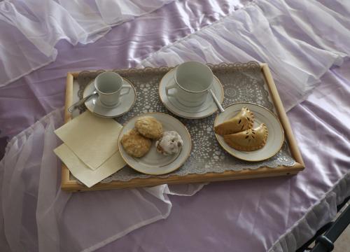 a tray with two plates of food and cups and cookies at Nonna Ninna B&B in San Floro