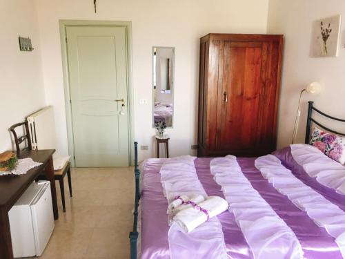 a bedroom with a bed with purple sheets and a wooden door at Nonna Ninna B&B in San Floro