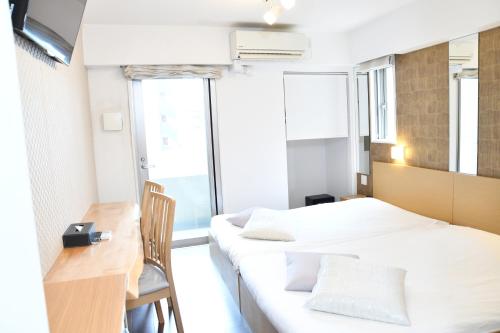 Habitación pequeña con 2 camas, escritorio y ventana. en Hotel Axas Nihonbashi en Tokio