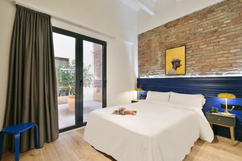 a bedroom with a white bed and a brick wall at Arte Suites by Olala Homes in Hospitalet de Llobregat