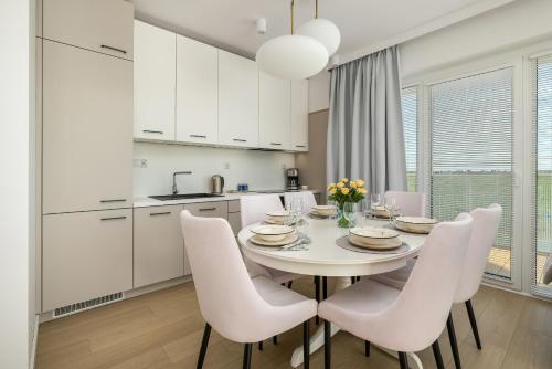 a kitchen and dining room with a white table and chairs at Family Apartment with Gym and Swimming Pool by Renters Prestige in Kołobrzeg