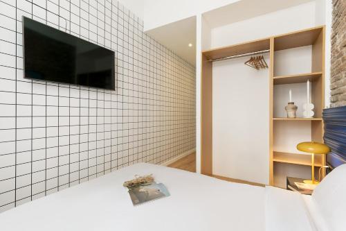 a bedroom with a tv on a white tiled wall at Arte Suites by Olala Homes in Hospitalet de Llobregat