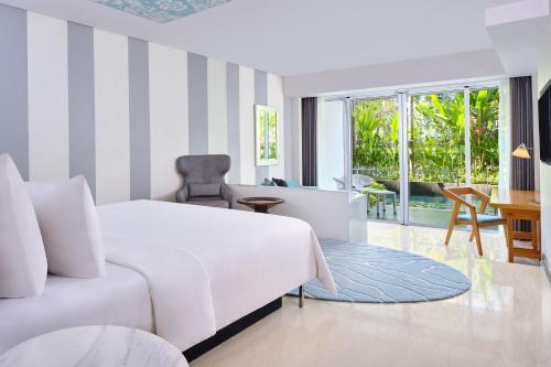 a bedroom with a large white bed and a desk at Le Meridien Bali Jimbaran in Jimbaran