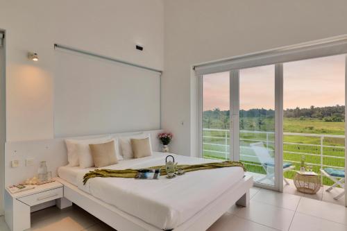 ein weißes Schlafzimmer mit einem großen Bett und einem großen Fenster in der Unterkunft Elivaas Risaia Luxe 4BHK Villa with Pvt Pool, Nerul in Nerul