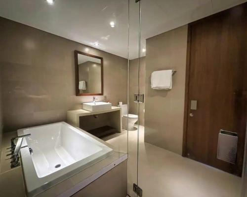 a bathroom with a tub and a sink and a mirror at Alacarte Luxury Ocean View Condotel in Da Nang