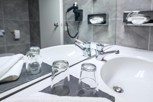 two glasses on a bathroom sink with a mirror at ACHAT Hotel Monschau in Monschau