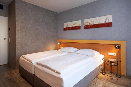 a bedroom with a large bed and two pictures on the wall at ACHAT Hotel Monschau in Monschau