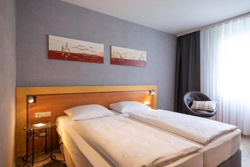 a bedroom with a bed and a chair at ACHAT Hotel Monschau in Monschau