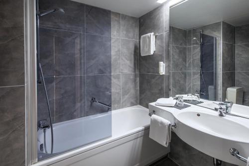 a bathroom with a tub and a sink and a bath tub at ACHAT Hotel Monschau in Monschau
