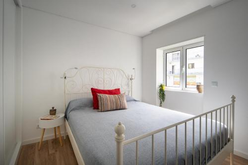 um quarto branco com uma cama com uma almofada vermelha em Apartamento Rodrigo na Covilhã