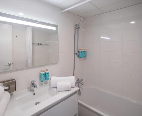 a white bathroom with a sink and a mirror at Novotel Nantes Centre Gare in Nantes