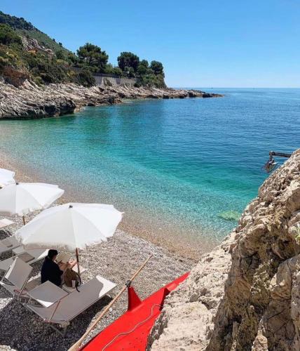 two people sitting in chairs under an umbrella on a beach at Casa Primavera in Ventimiglia