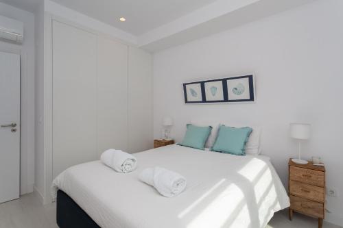 um quarto com uma cama branca e toalhas em Alto das Vinhas Lovers - Sesimbra em Sesimbra
