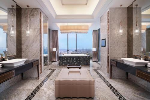 a bathroom with two sinks and a bath tub at Sheraton Qingdao Licang Hotel in Qingdao