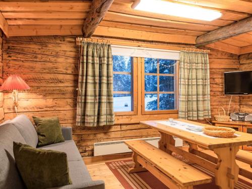 Cette cabane en rondins comprend un salon avec une table et une télévision. dans l'établissement Holiday Home Senaattori 1 by Interhome, à Ylläsjärvi